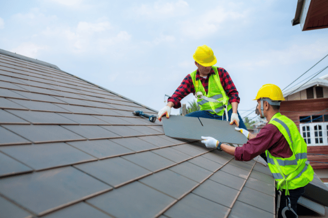 Image of Home with two builders fixing roof tiles