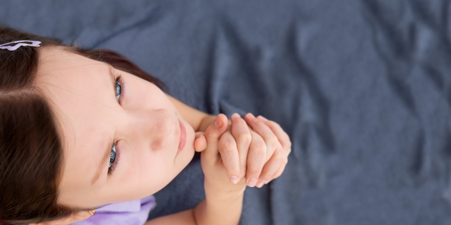 Image of young girl with hands clasped looking up in prayer