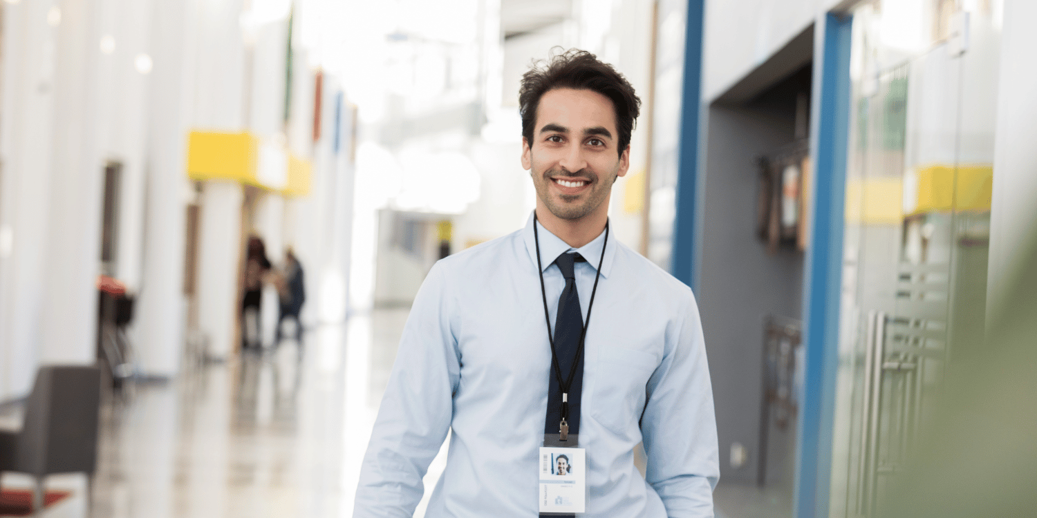 Man standing in school corridor holding a file