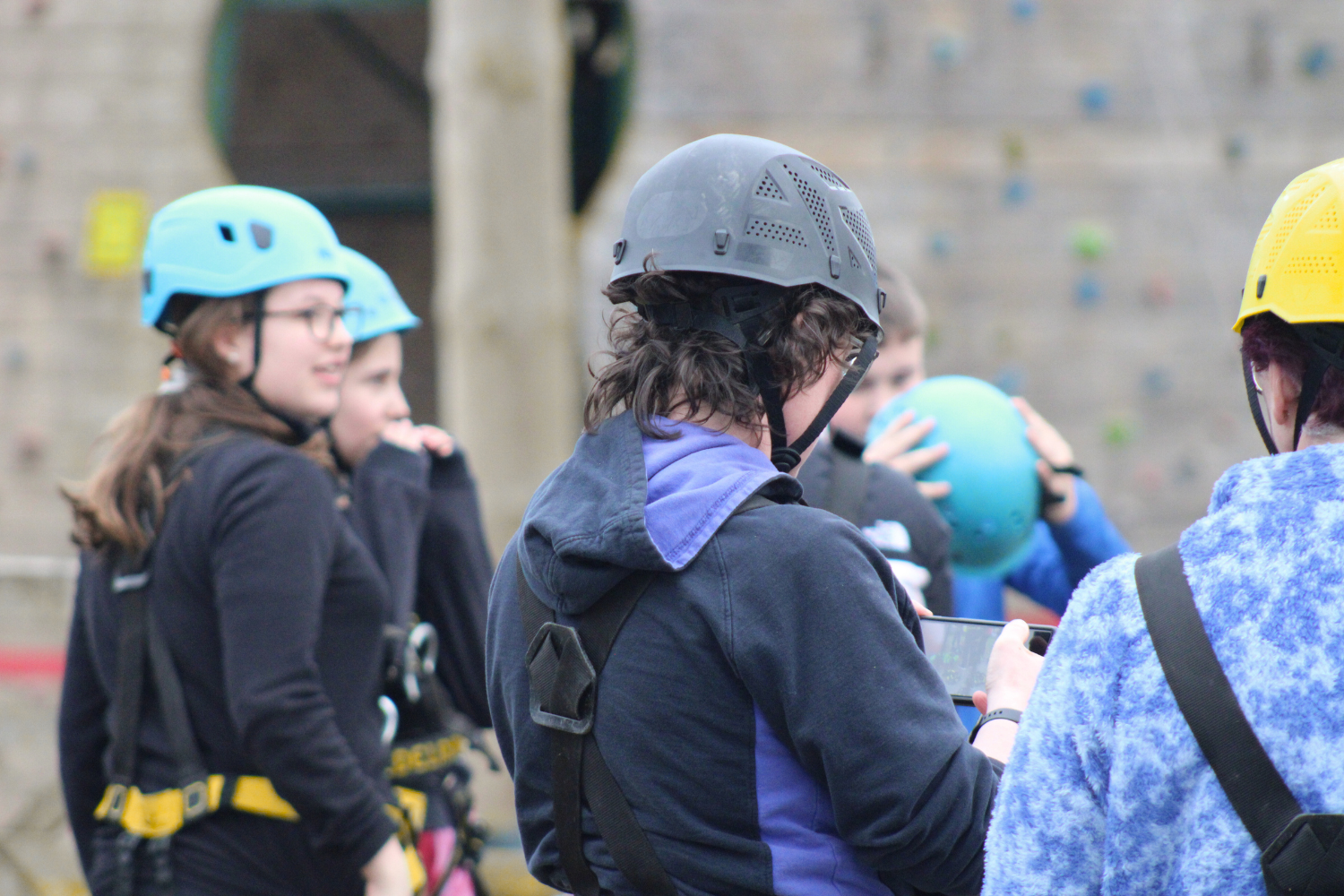 Young People in climbing harnesses standing next to a climbing wall