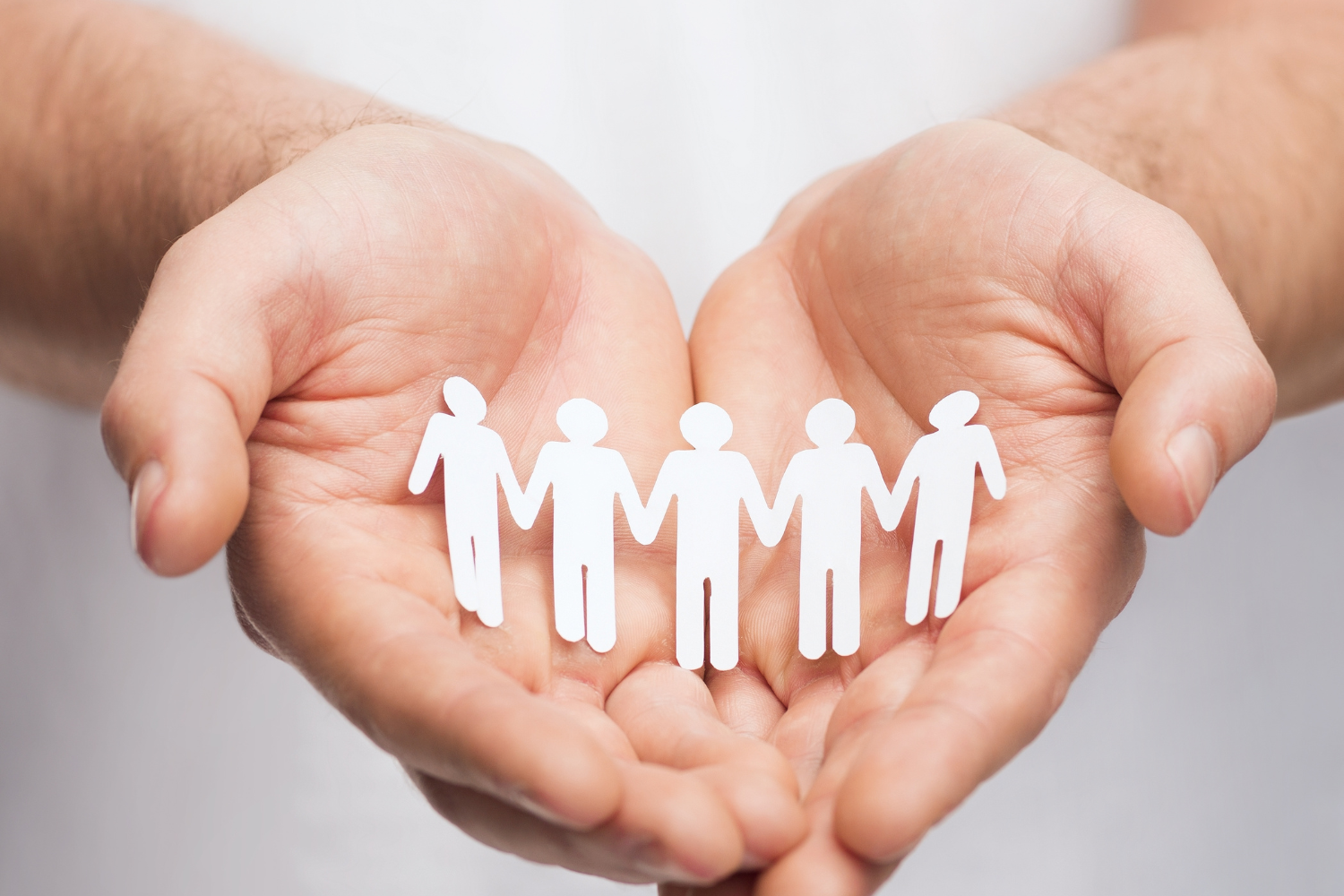 Image of hands hold paper cut outs of people