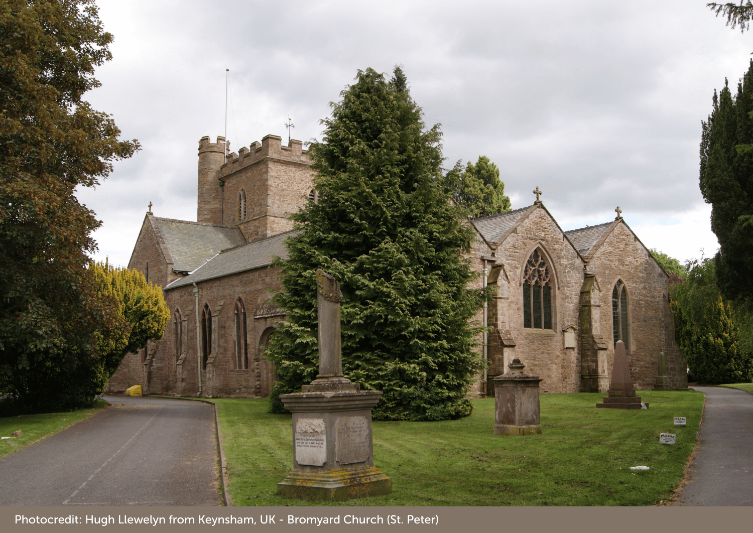 Picture of a church looking up the church path towards the building.  Blue sky and trees