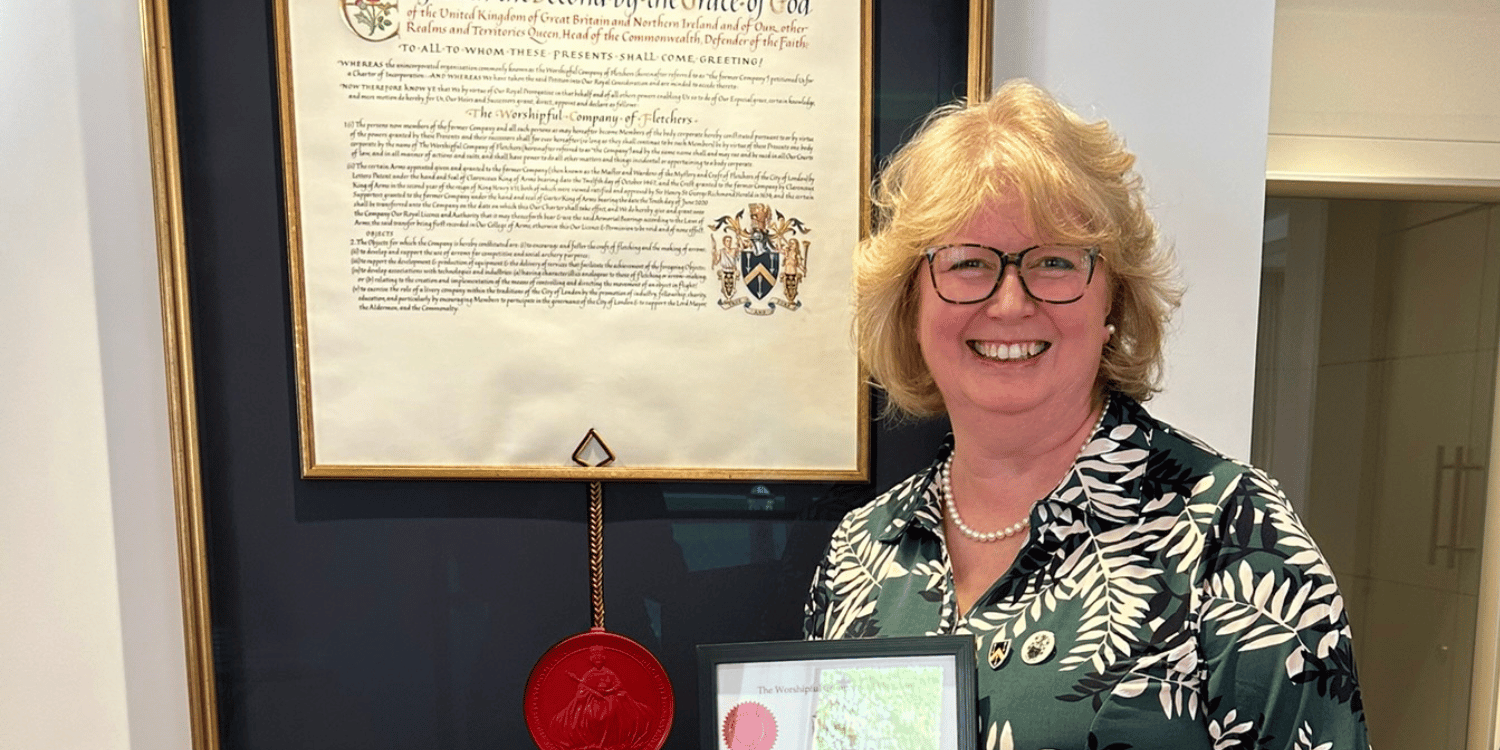 Lesley Grady stood in front of large certificate on wall holding small certificate