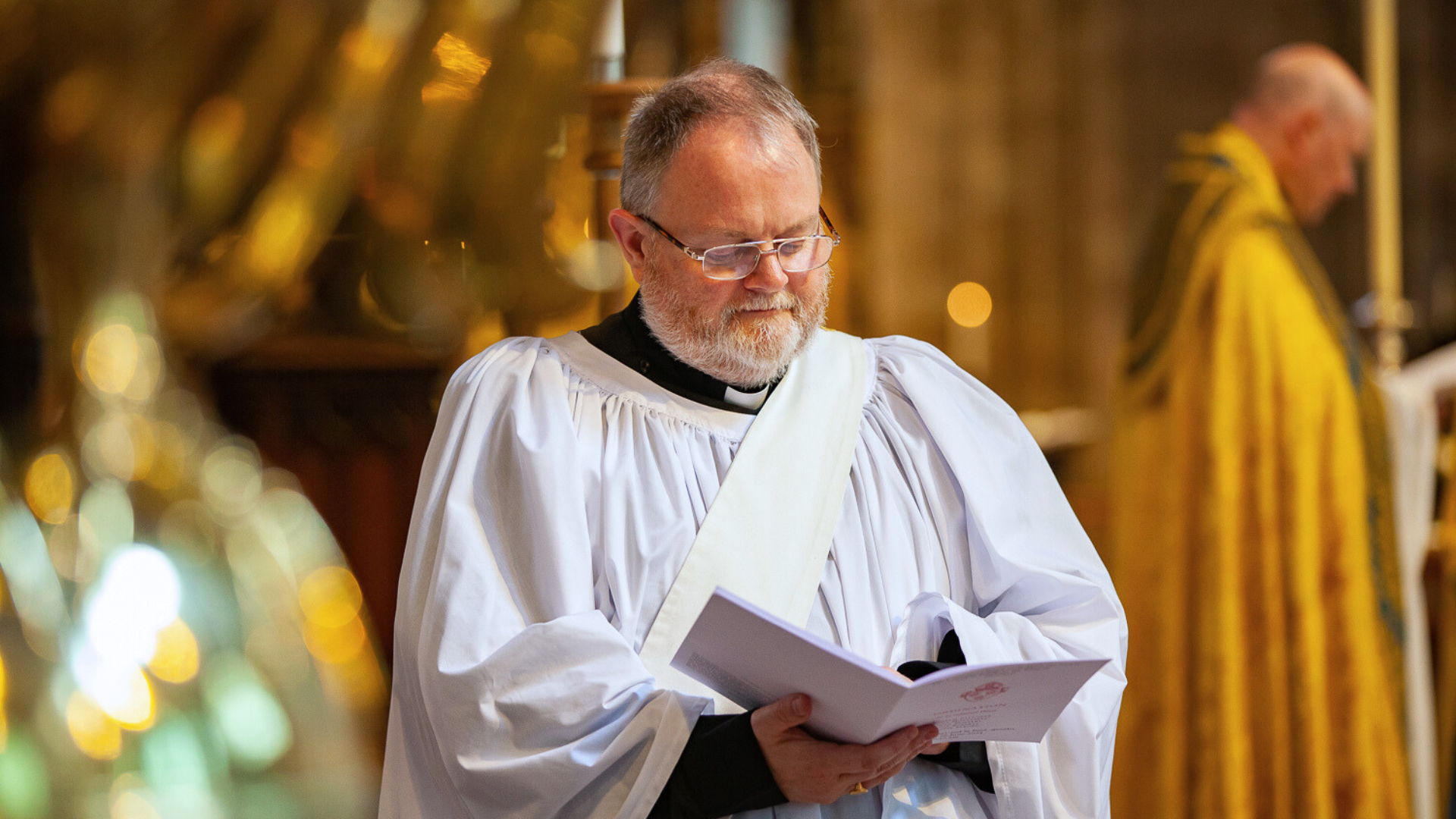 Clergy person stood at the front of church reading the service sheet