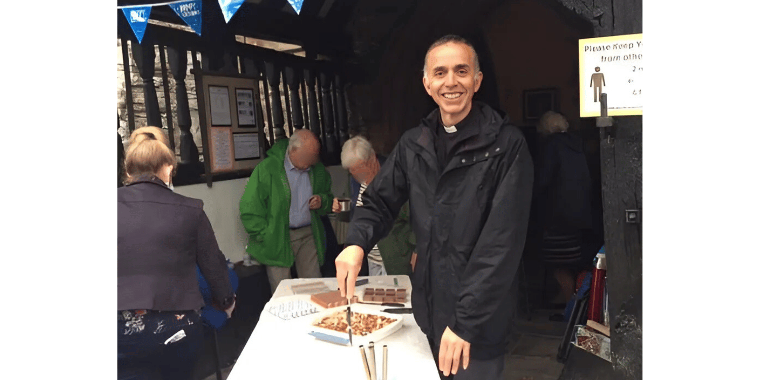 Revd David Moss in the porch of Worthen Church cutting a cake