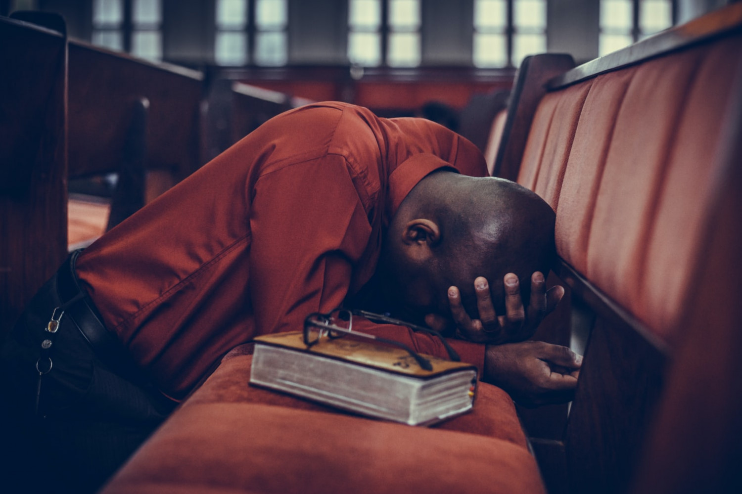 A man kneeling at a pew in prayer