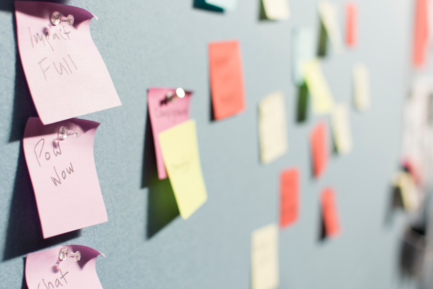 Image of a notice board covered in different coloured Post-It notes