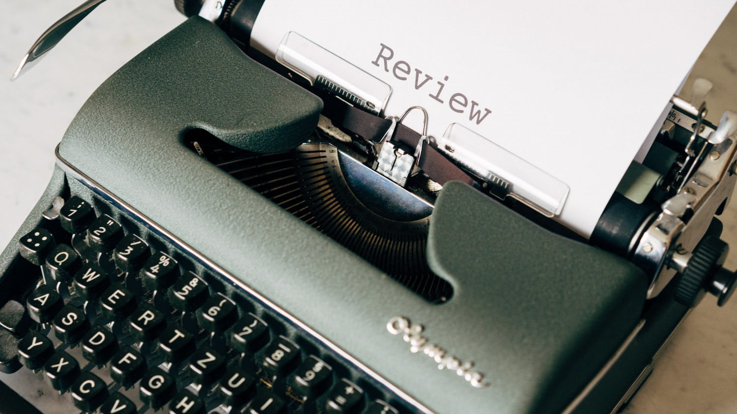 Image of a black typewriter with the word 'review' written on the paper