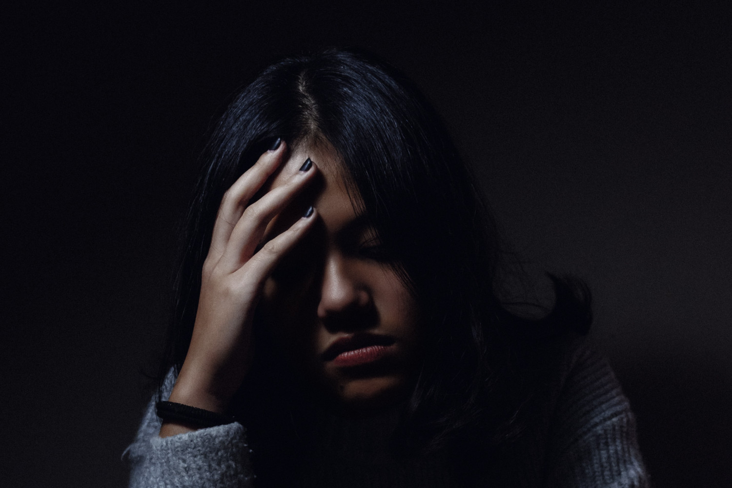 Image of a woman, palm partially obscuring her face