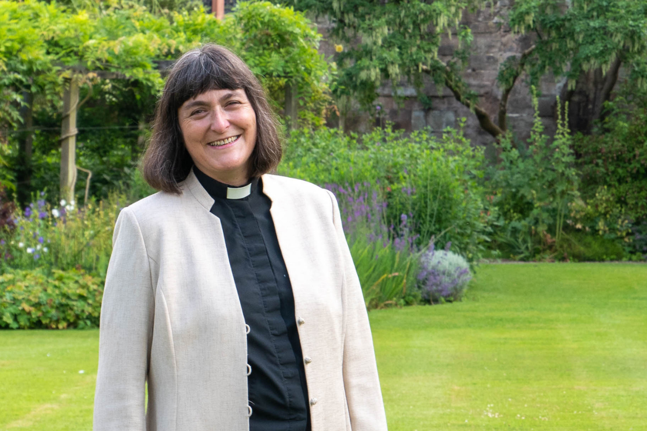 Dean of Hereford, The Very Revd Sarah Brown in garden with Hereford Cathedral in background